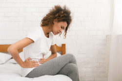 A woman holds her stomach in pain.