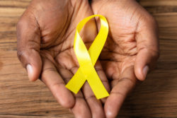 Two hands hold a yellow ribbon.