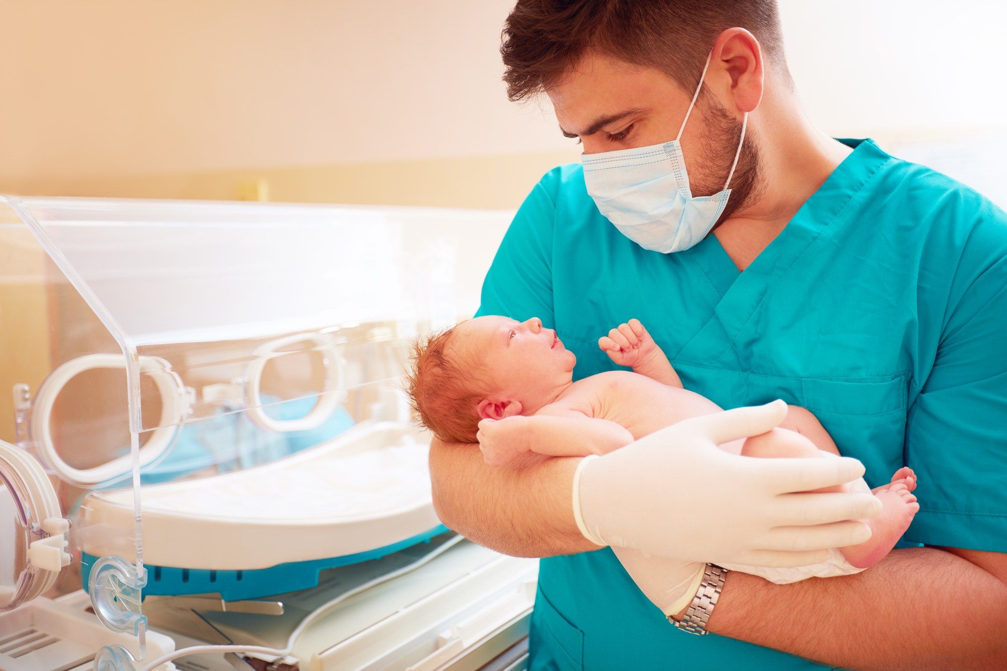 Young man holds newborn baby in hospital