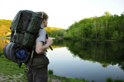 A boy scout looks at a lake.