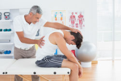 A chiropractor stretches a man's back.