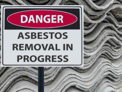 Danger asbestos removal sign in front of roofing material