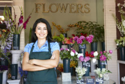 A florist stands outside a flower shop.