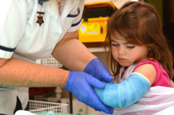 A nurse helps a girl with a broken arm.