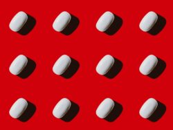 White pills on red background