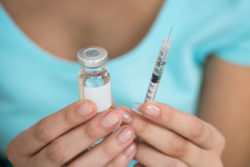 Woman holding a vaccine bottle and syringe