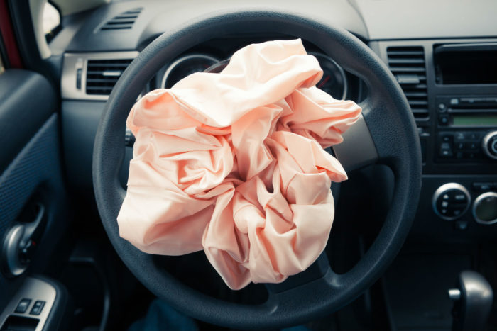 A car's airbag is deployed but not inflated.
