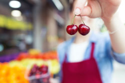 Grocery store worker holding up cherries