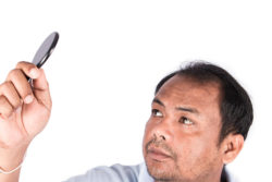 Man looking at thinning hair with small mirror