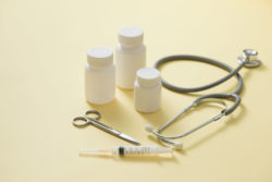 Medicine bottles and stethoscope on yellow background