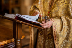 Priest read to congregation from scripture book during sermon on sexual abuse