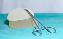 Two textured breast implants and a hemostat