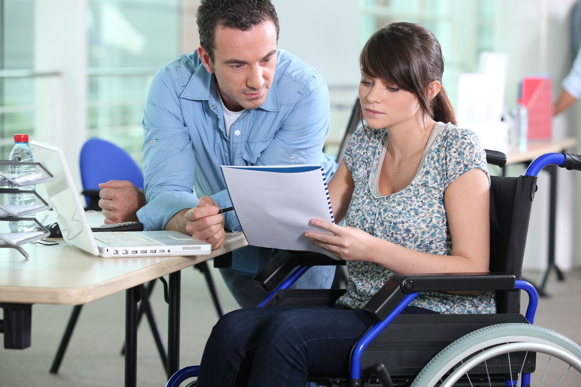 Woman in wheelchair reviews disability insurance coverage with a male colleague.