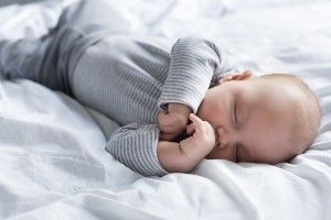 Sleeping baby wearing a grey striped onsie - baby has cerebral palsy