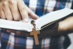 Close up of man holding bible with a cross