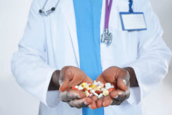 A doctor holding a bunch of pills, some of which may be the HIV/Aids drug Truvada, alleged to cause kidney damage.