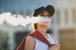 A girl blows smoke into the wind.