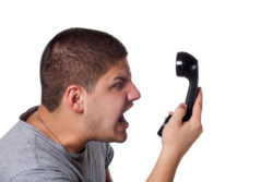 Man fed up with telemarketer calls screams at phone.
