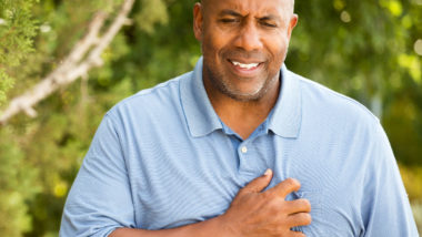 A man holds his chest in pain.