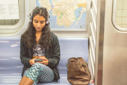 A woman checks her phone on the subway.