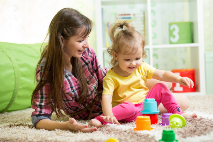 au pair playing with little girl and toys