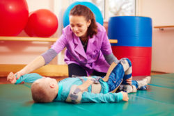 A physical therapist works with a boy.