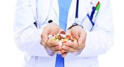 A doctor holds a handful of pills.