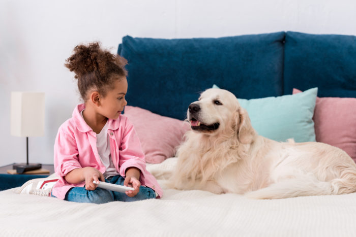 girl with her pet dog sitting on bed