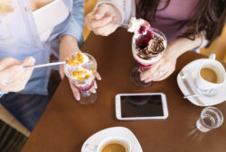 Two women eat ice cream at a table.