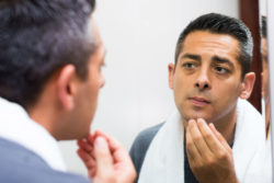Man examining skin in mirror
