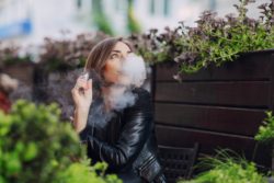 young woman smoking ecigarette outside