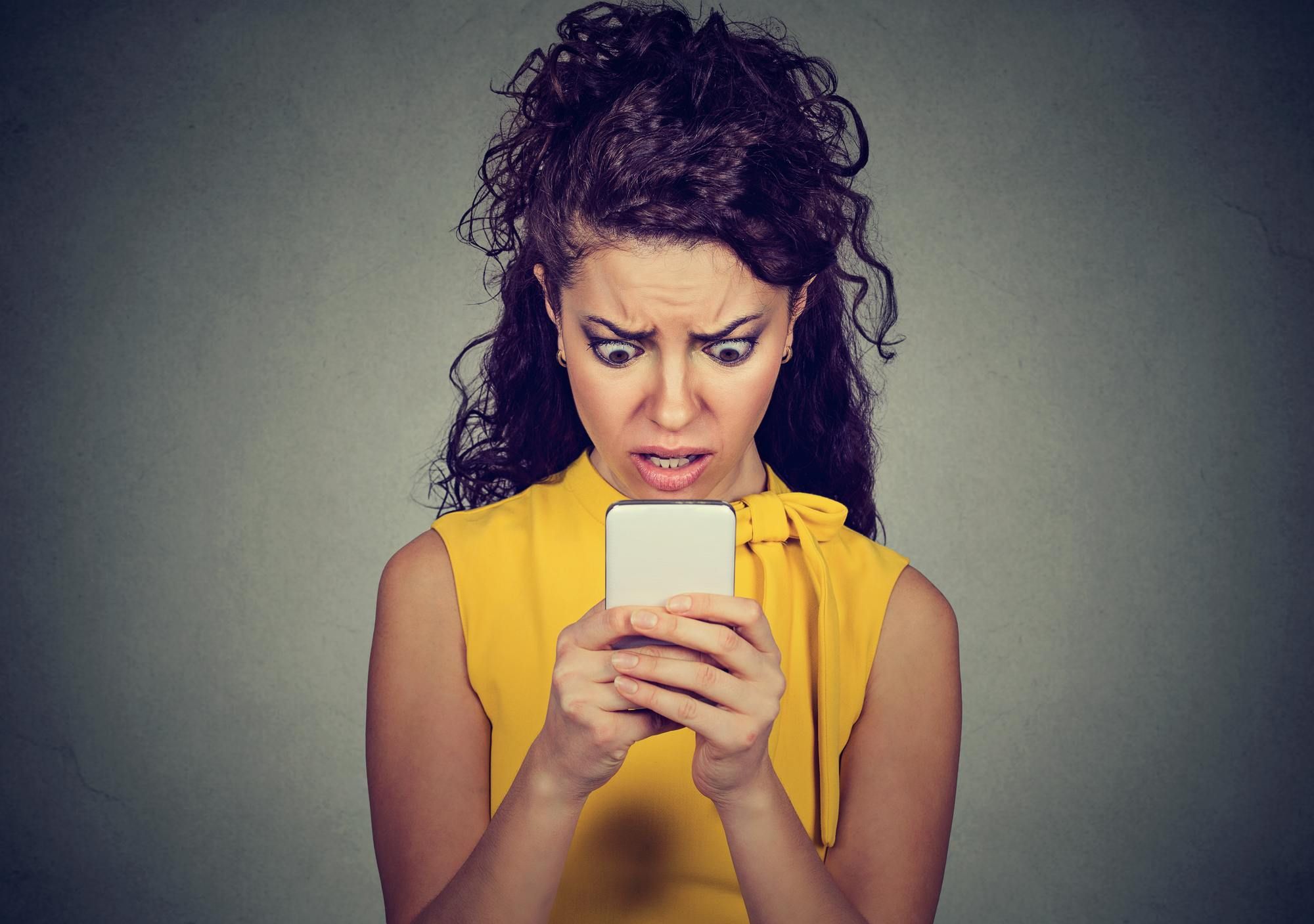 Portrait anxious scared girl looking at phone seeing bad message