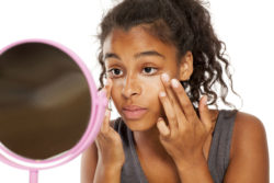 A woman uses a mirror to apply makeup.