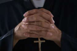 Close-up of priest's hands praying