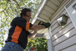A man fixes exterior trim on a house.