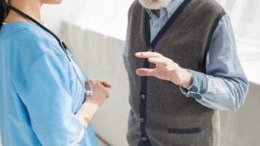 Man gesturing while talking to nurse