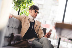 A man sits on a sofa and looks at a smartphone.