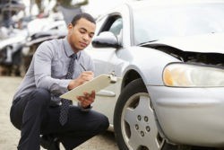 Insurance adjuster examining car