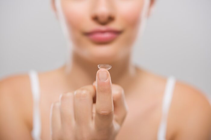Focus on contact lens on finger of young woman.