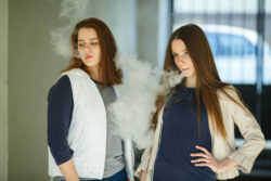 Two girls use e-cigarettes.