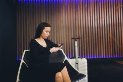 A woman waits with her smartphone in a hotel lobby.