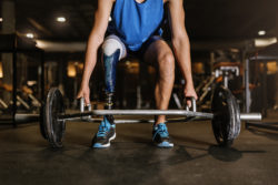 A man with a prosthetic leg lifts weights.