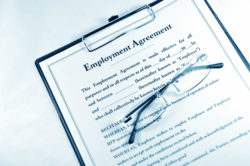 Employment agreement with folded glasses on clipboard