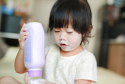 A girl plays with a bottle of talcum powder.