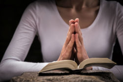 A woman prays over a bible.