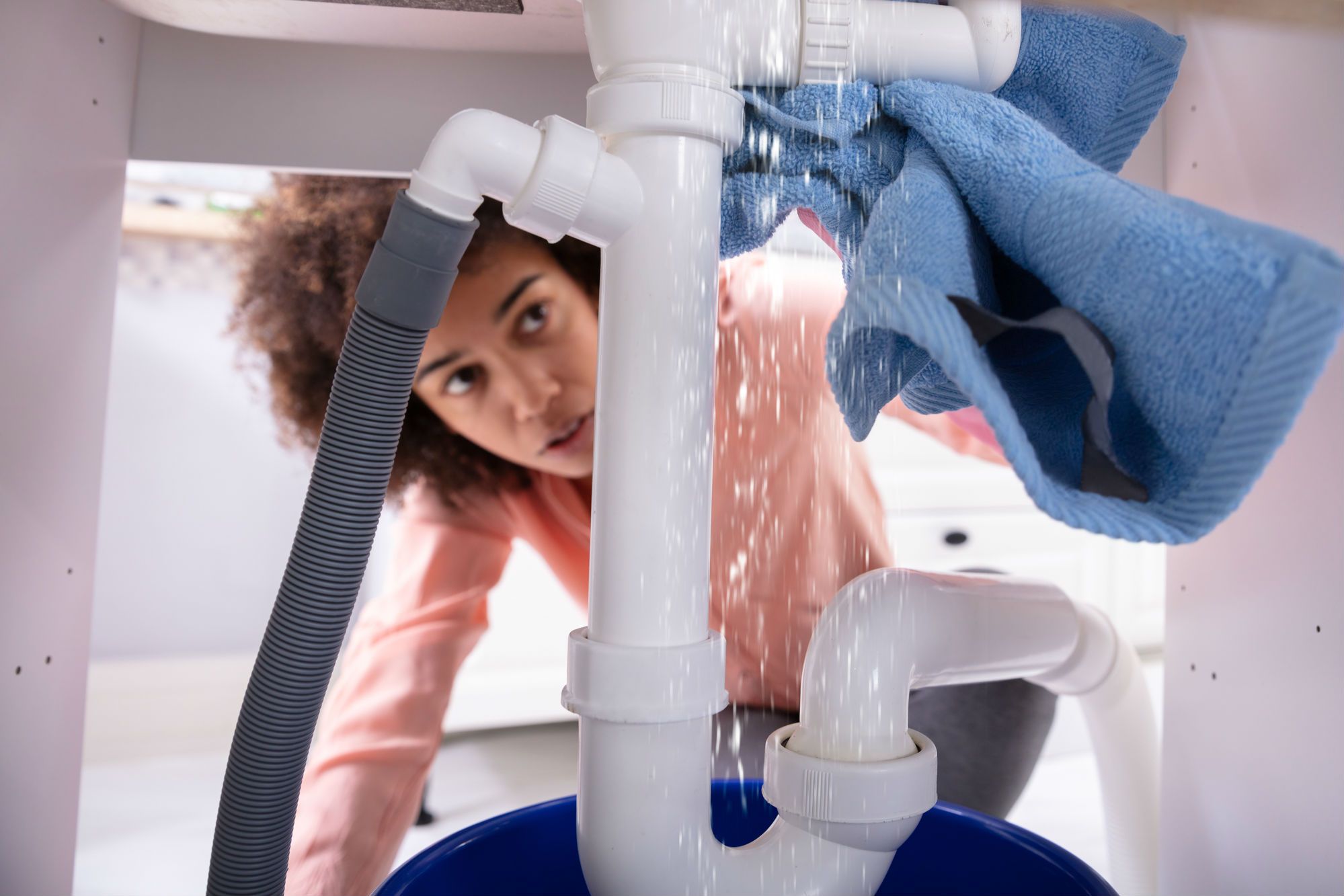 A woman fixes a leaky sink.