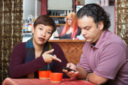 A woman points at a man's phone.