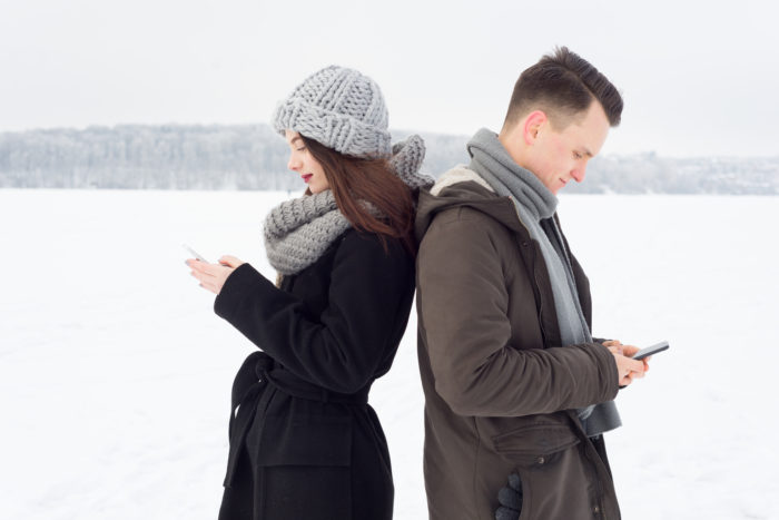 couple on iphone and android phones in winter