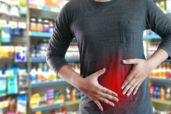 A man has stomach pain while standing in a drugstore.