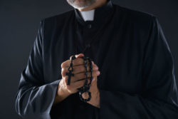 Priest praying with rosary